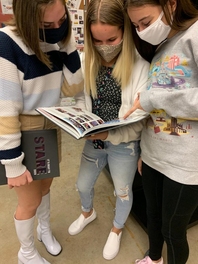 Maggie Butler (10th), Braydon Fleck (10th), and Abby Dell (10th) flip through the yearbook, looking at people and events they recognize. 