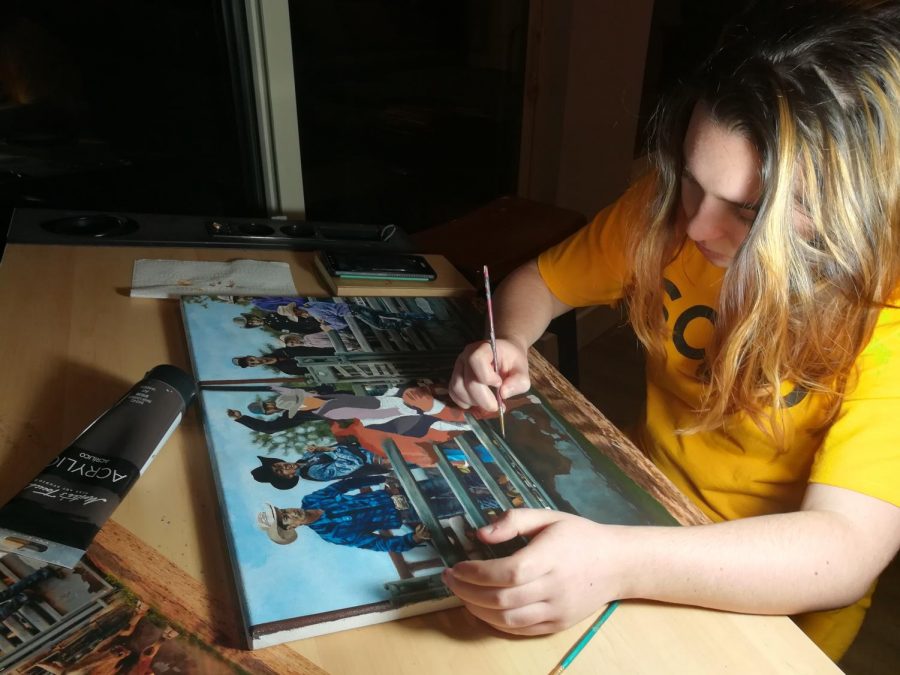 Jordan works on her submission for a rodeo art contest at her desk. The painting is based on a photograph showing onlookers at a rodeo watch a bull buck its rider.