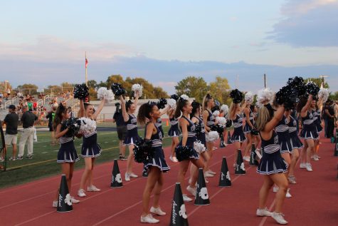 Cheerleaders performing for the student section during a home varsity football game this fall.