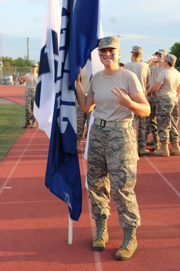 Senior Sarah Gardner holding a Champion High School flagpole and sporting her ROTC camouflage uniform.