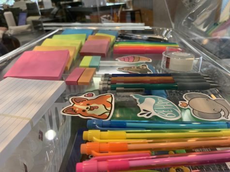A shelf of the Little Library Store, featuring pens, pencils, sticky notes, note cards, stickers, and more. There are also more stickers and squishies available to browse at request.